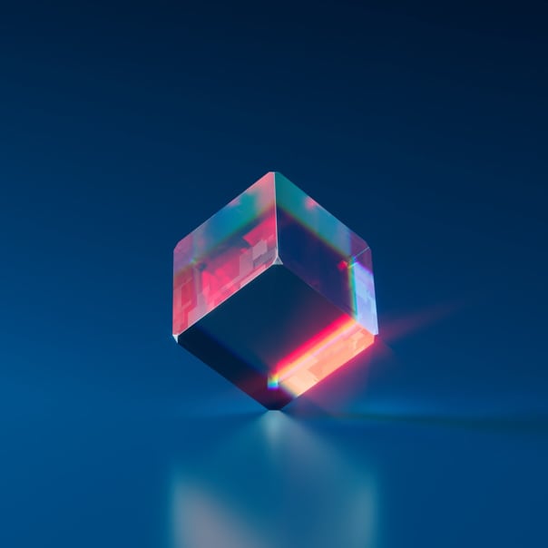 A colorful glass cube balancing on one of its corners on a shiny blue surface in front of a blue background