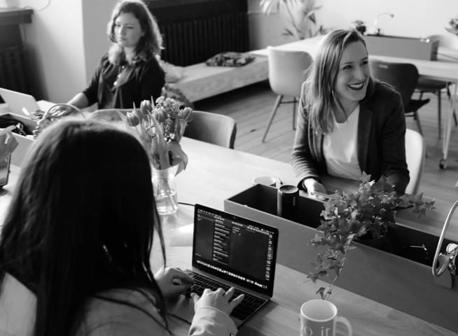 3 women working at a shared desk on laptops